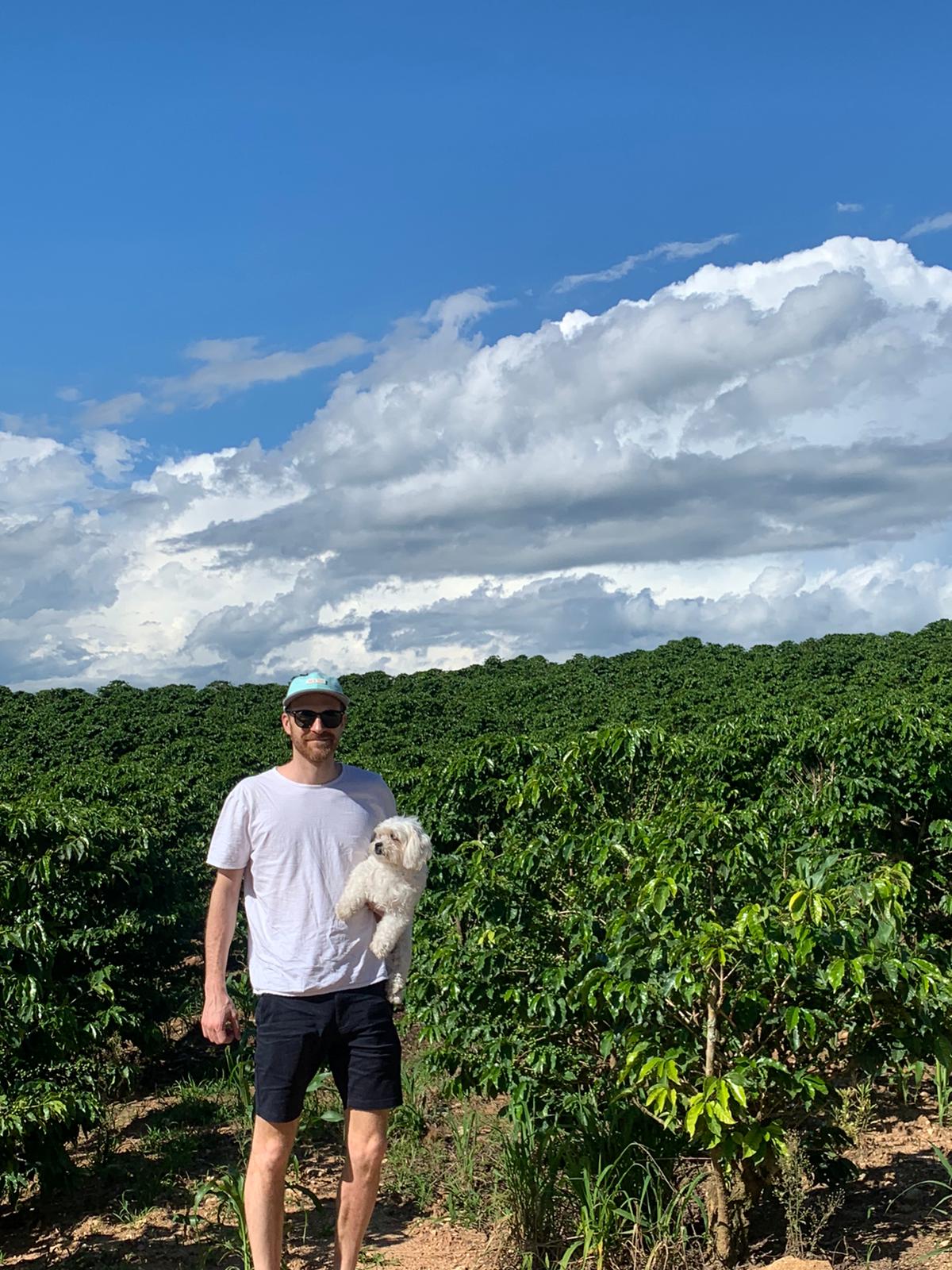 The founder of Esspero standing in a coffee plantation holding a dog 